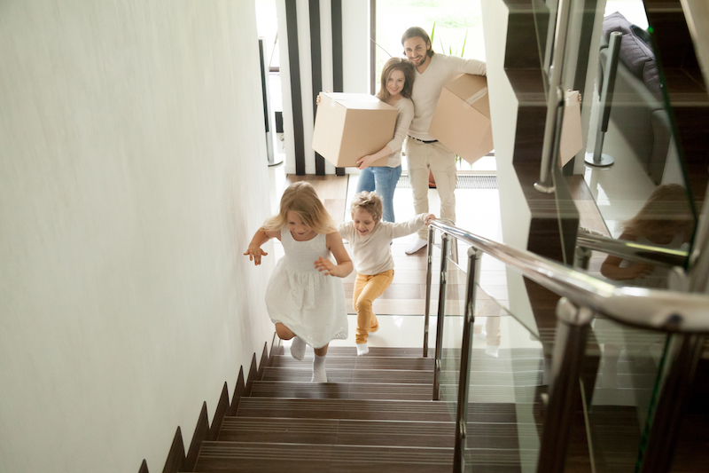 Buying a New Home? Consider These Insurance Factors family carrying in boxes to their new home